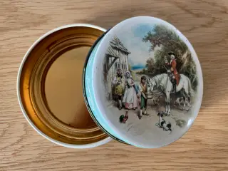 Rund gammel dåse med et billede af en jagtscene