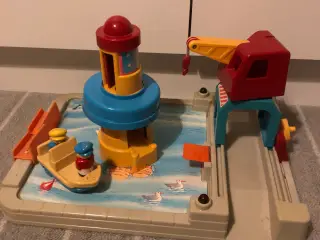Kran ved havn med båd og fyrtårn