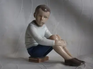 Dreng siddende på bøger, figur,Bing & Grøndahl